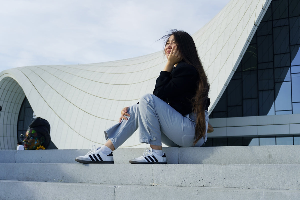 Young woman sitting on steps near modern building