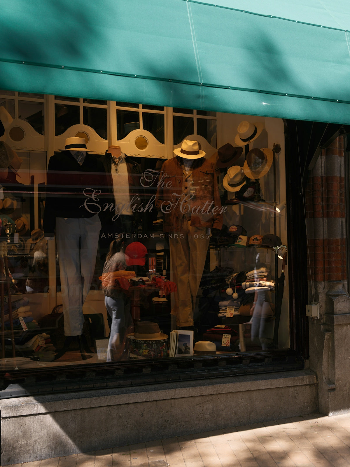 Hats displayed in a shop window with mannequins.